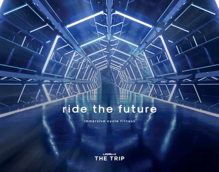 An illuminated futuristic tunnel with angular, metallic structures and bright blue-white LED light strips lines the walls and ceiling, creating a sense of depth and motion. Reflections on the glossy floor enhance the immersive, sci‑fi atmosphere. Centered text reads “ride the future” with the subtitle “immersive cycle fitness,” and below that the branding “LES MILLS THE TRIP.”