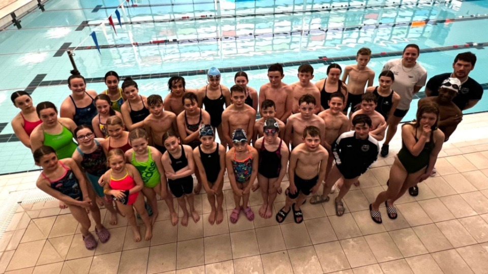 Swimming class students by the side of the pool