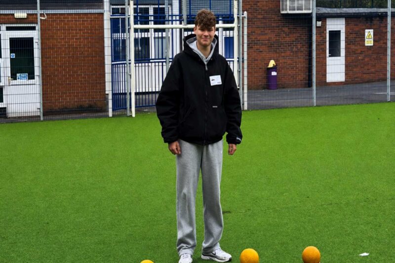 Student on work experience at Oldham School stood on football pitch